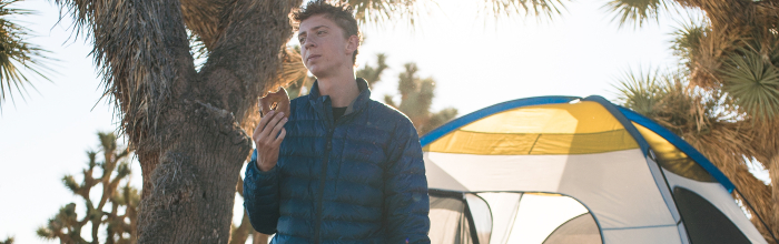 Picture of camper eating food next to tent